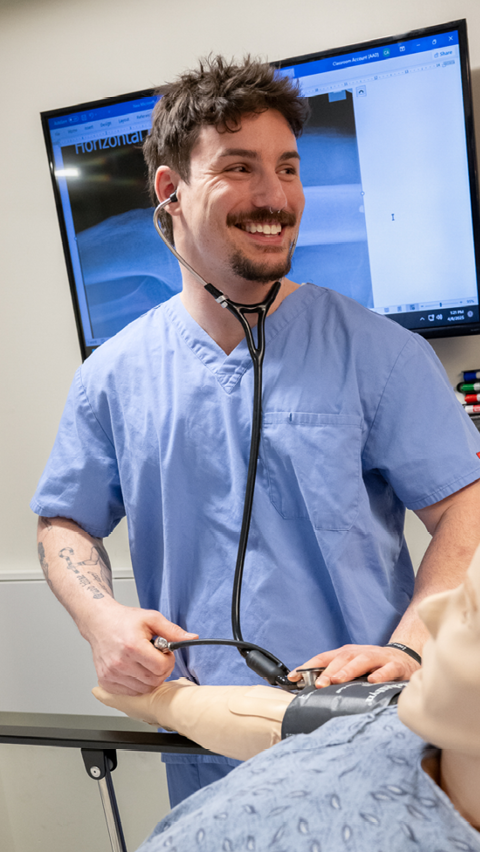 Smiling MCPHS student in scrubs with stethoscope. 