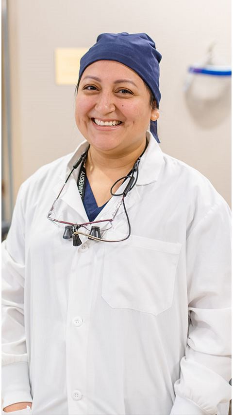 Female faculty member in white coat smiling. 