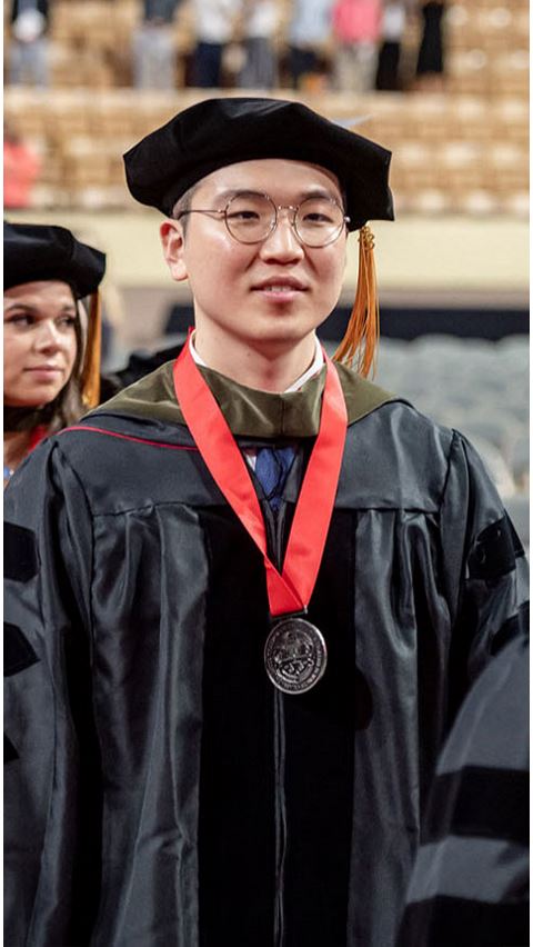 Male student wearing a cap and gown. 