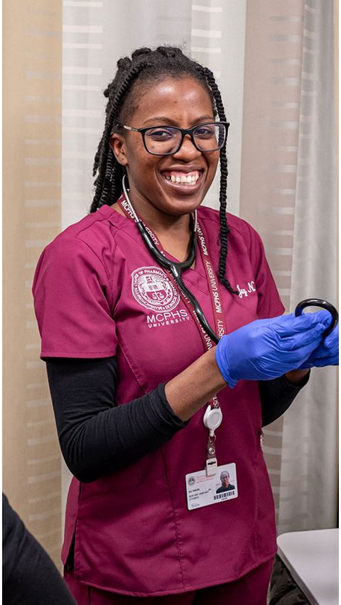 Female student smiling in scrubs. 
