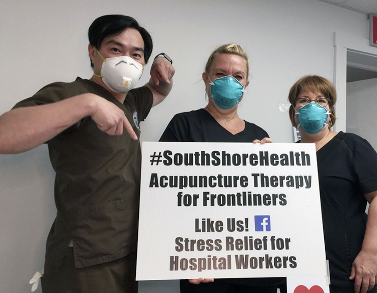 three people by a sign that says #SouthShoreHealth Acupuncture Therapy for Frontliners Like Us! Stress Relief for Hospital Workers