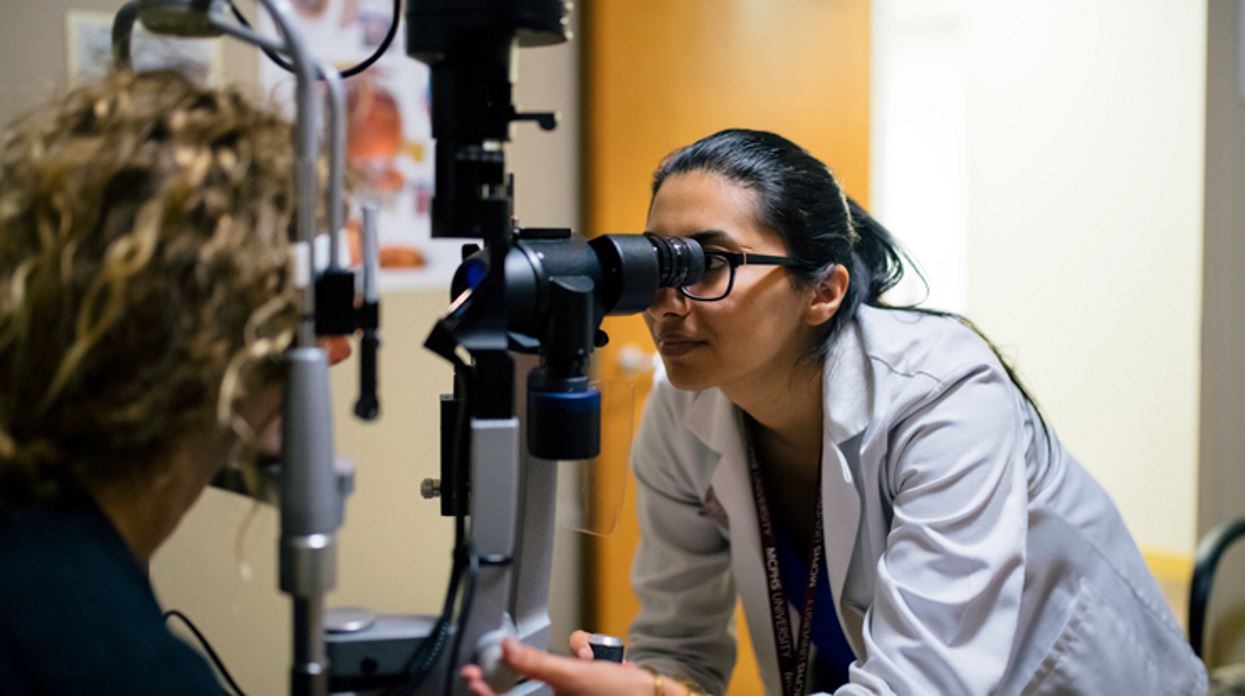 MCPHS optometry student conducts an eye exam on a patient