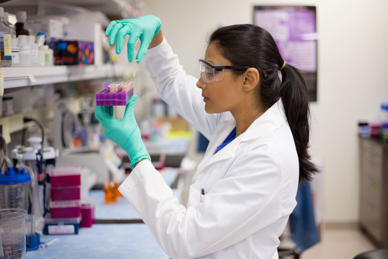 Female in white lab coat working in a lab. 